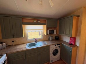 Cocina compacta con lavadora, microondas y lavabo.