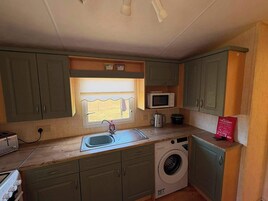 Cocina compacta con lavadora, microondas y lavabo.