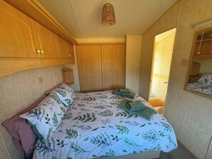 Un dormitorio con cama, armario de madera y lámpara colgante.