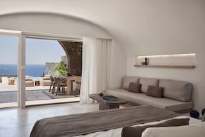 Ein modernes Schlafzimmer mit einer Couch, einem kleinen Tisch und Blick aufs Meer.
