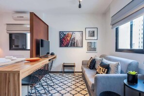 A modern living room with a sofa, a coffee table, a TV, and artwork on the wall. - Advance by Bhomy (São Paulo)