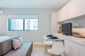 Een modern appartement met een bank, eettafel en een televisie in de keuken.