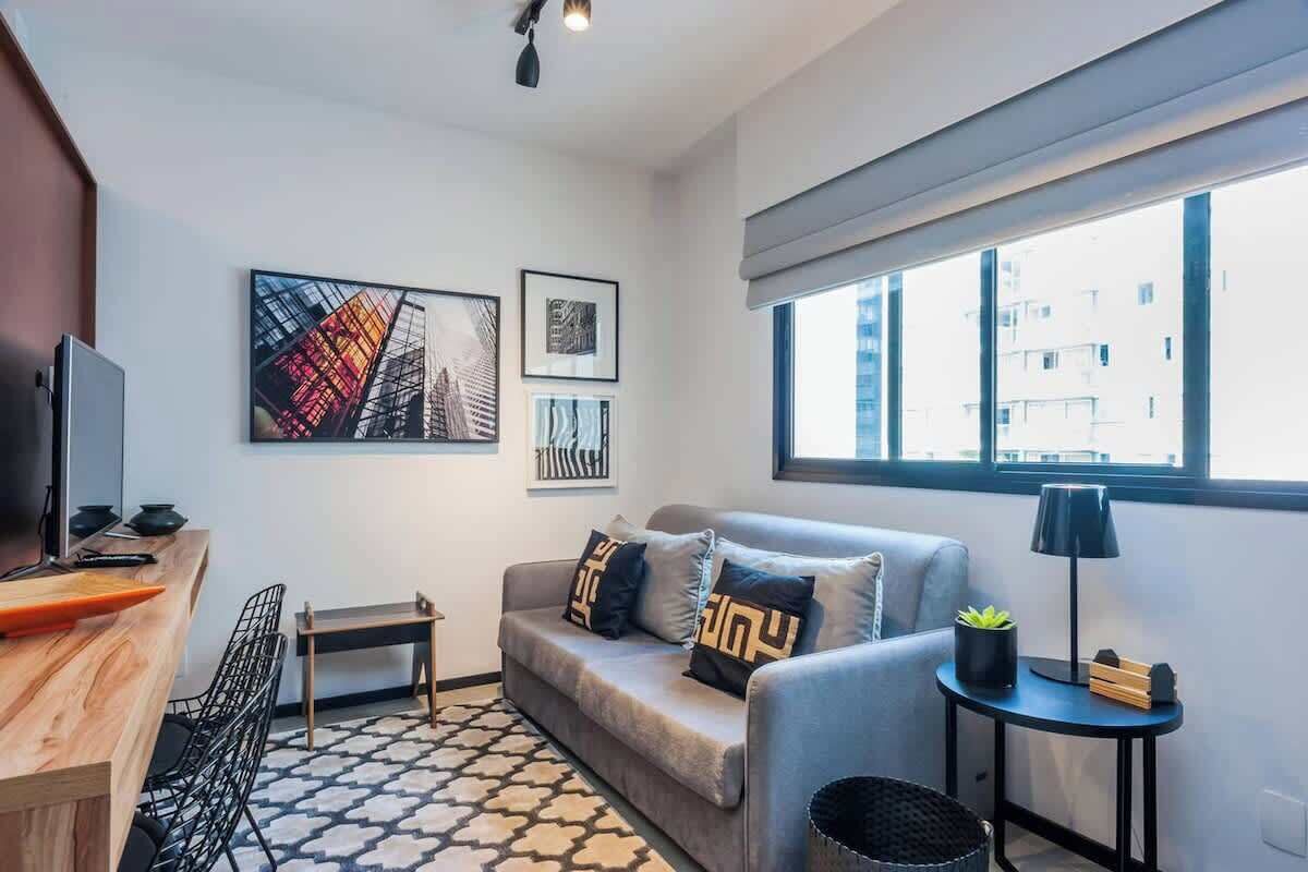 Una sala de estar moderna con un sofá, una mesita, un televisor y obras de arte en la pared.