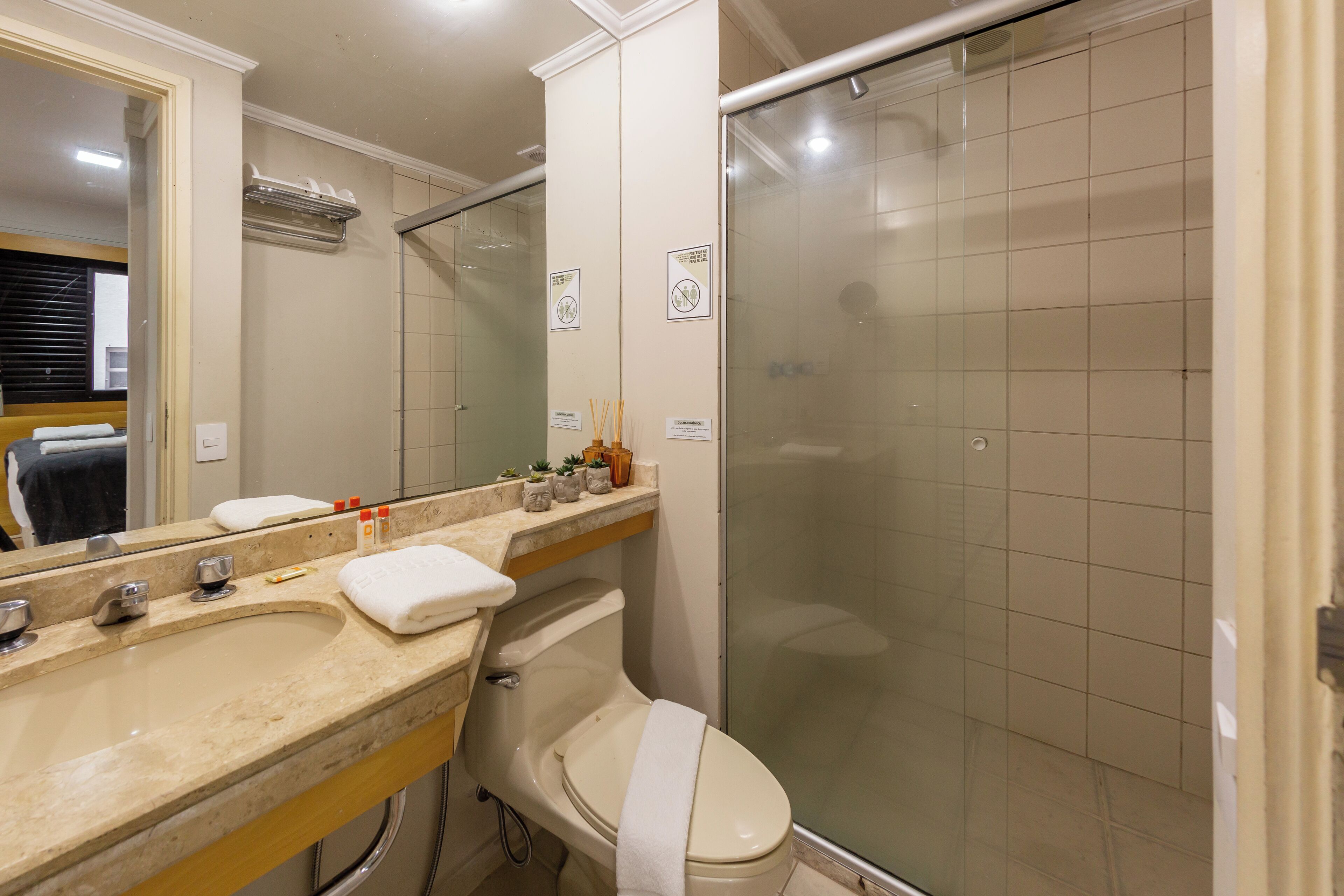 A bathroom with a sink, mirror, toilet, and shower.