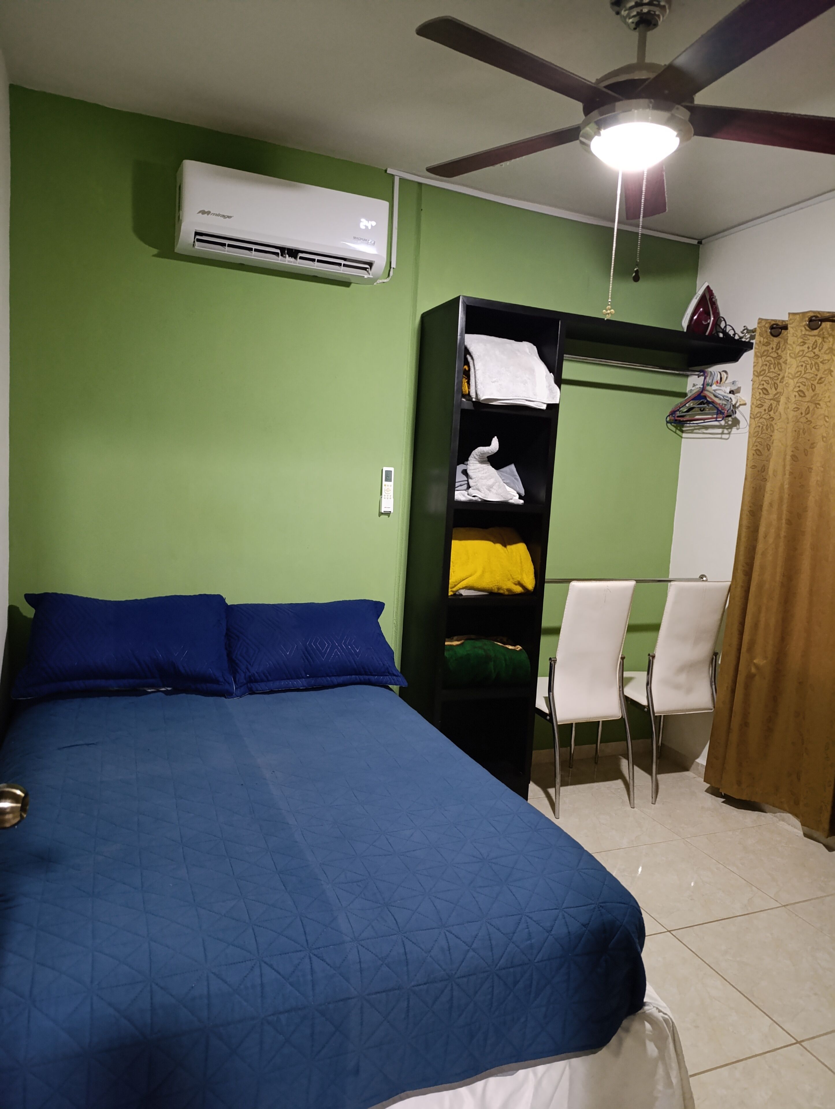 Ein Zimmer mit einem Bett, einem Kleiderschrank, einem Schreibtisch und einer Klimaanlage.
