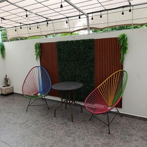 An outdoor seating area with two chairs and a table, surrounded by a pergola with string lights. - A nice, cozy apartment with air conditioning. (Ecoterra Paraíso)