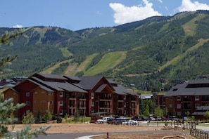Un hotel a più piani dal design architettonico moderno, situato in una zona montana con piste da sci visibili sullo sfondo.