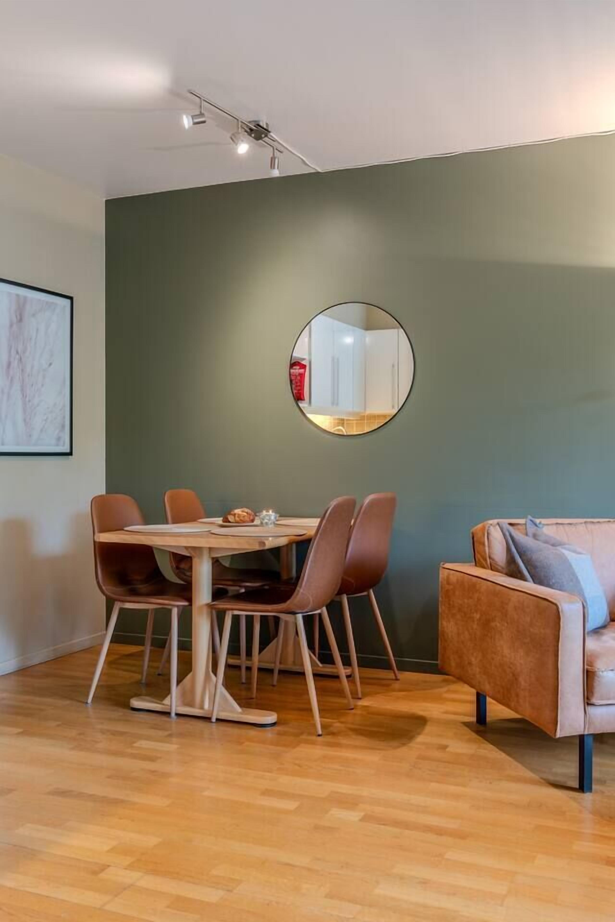 A dining area with a round table, four chairs, and a sofa.