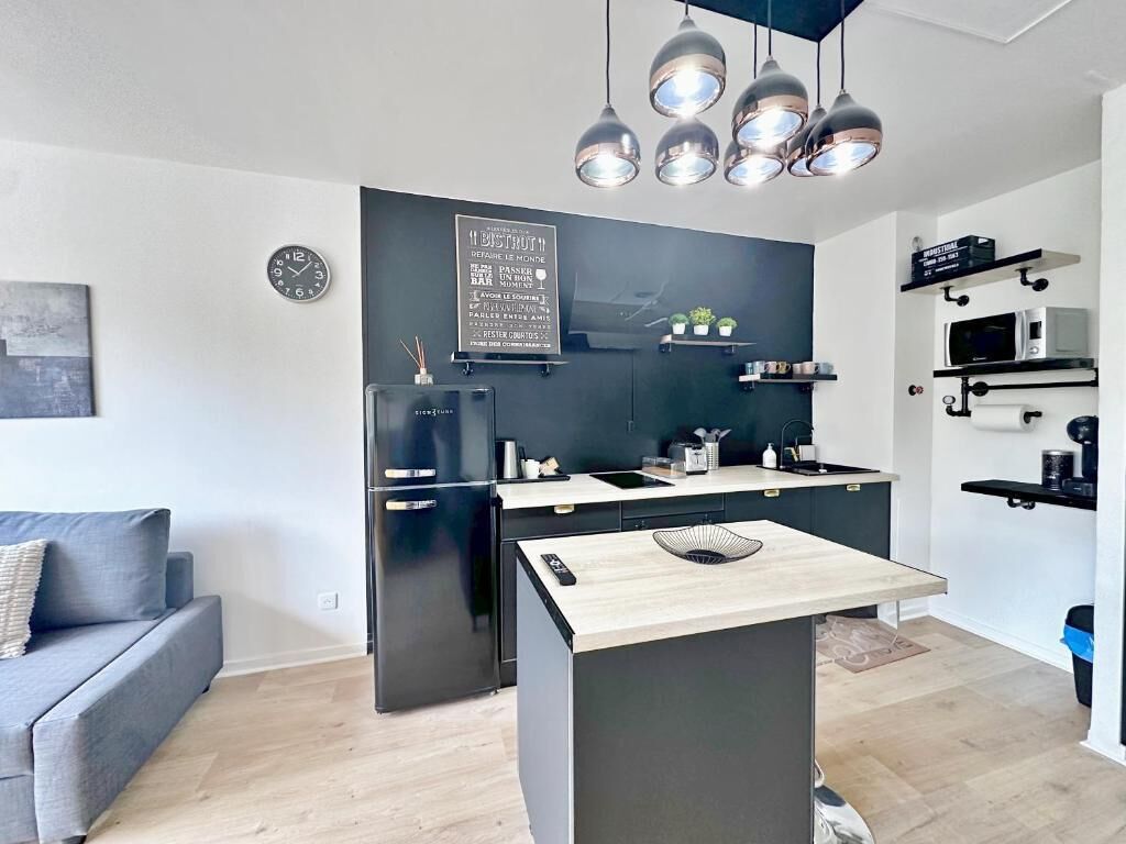 A modern kitchen with a central island, black appliances, and pendant lighting.
