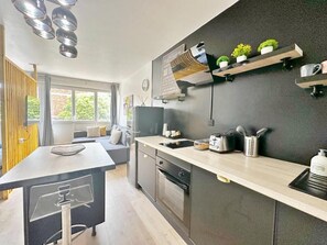 Una cocina moderna con una isla central, electrodomésticos integrados y un salpicadero oscuro.