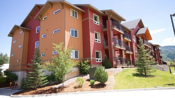 A multi-story hotel with balconies, a landscaped garden, and a mountainous backdrop.