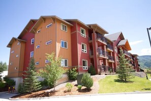 A multi-story hotel with balconies, a landscaped garden, and a mountainous backdrop. - WM BLOCK Steamboat 1br (Steamboat Springs)