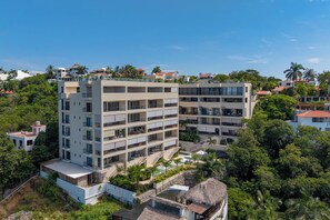 A multi-story hotel with balconies, surrounded by lush greenery and palm trees. - Luxury in Huatulco Ocean View & Pool (Santa María Huatulco)