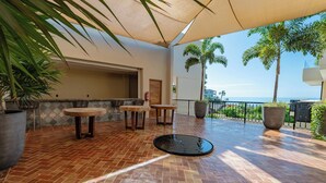 Un patio exterior con suelo de baldosas, dos mesas redondas y sillas.