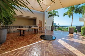 Eine Terrasse im Freien mit Fliesenboden, zwei runden Tischen und Stühlen.