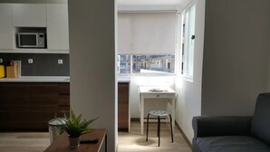 A modern kitchen with a microwave, a dining area with a table and chairs, and a view of the outside. - One-bedroom apartment 150 meters from Praia da Rocha (Portimão)