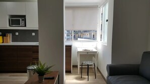 Eine moderne Küche mit Mikrowelle, ein Essbereich mit Tisch und Stühlen sowie ein Blick ins Freie.