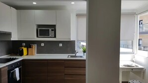 A modern kitchen with a microwave, toaster, and sink. - One-bedroom apartment 150 meters from Praia da Rocha (Portimão)