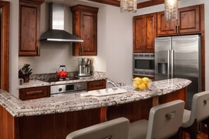 A kitchen with wooden cabinets, a stainless steel refrigerator, and a granite countertop. - Ritz-Carlton Vail Luxury 3BR/3.5 BA+Full Kitchen. Direct Access to Slope (Vail)