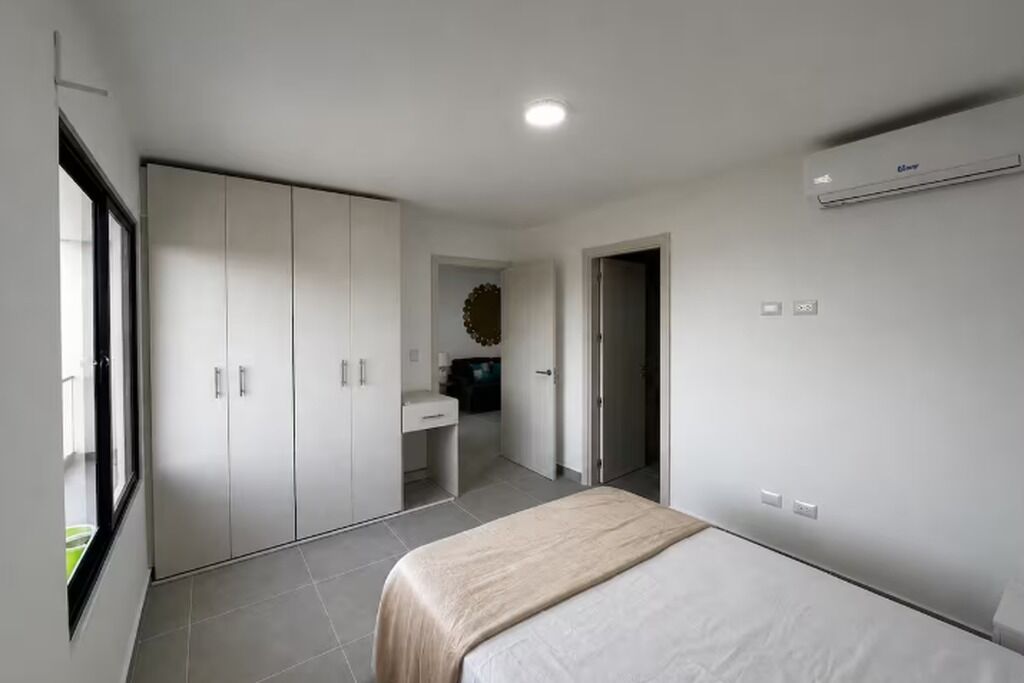 A bedroom with a bed, wardrobe, and a bathroom visible through an open door.