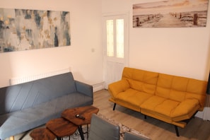 A living room with a blue sofa, a yellow sofa, and a small wooden table. - Contractors & Families pick- Racecourse,Shopping & Attractions-Parking (Doncaster)