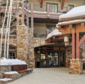 A multi-story building with stone walls, a wooden balcony, and a covered entrance area.