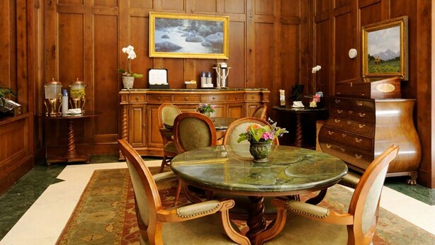 Une salle à manger élégante, avec une table ronde, des chaises, un buffet et un tableau accroché au mur.