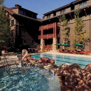 A hotel with a pool area, outdoor seating, and a stone facade. - Ritz-Carlton Aspen Ski-in Ski-out 3BR+3.5BA Luxury Residence with Full Kitchen (Aspen)