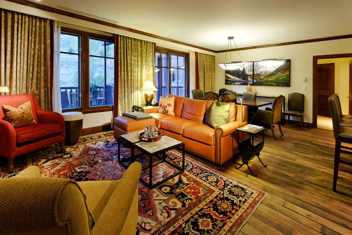 A living room with a red sofa, an orange sofa, a coffee table, and a patterned rug.