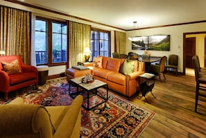 A living room with a red sofa, an orange sofa, a coffee table, and a patterned rug. - Ritz-Carlton Aspen Ski-in Ski-out 3BR+3.5BA Luxury Residence with Full Kitchen (Aspen)