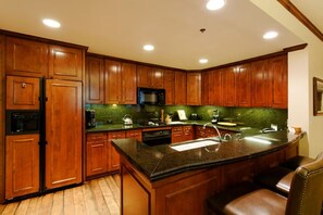 A kitchen with wooden cabinets, a granite countertop, and a stainless steel sink. - Ritz-Carlton Aspen Ski-in Ski-out 3BR+3.5BA Luxury Residence with Full Kitchen (Aspen)