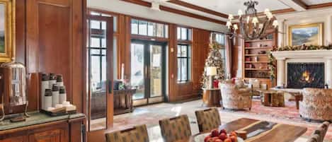 A spacious room with a large wooden dining table, comfortable seating, a fireplace, and a bookshelf.