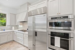 A modern kitchen with white cabinetry, a stainless steel refrigerator, a double oven, and a gas stove. - Beacons Beach Retreat | Steps from the Sand (Encinitas)