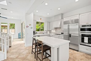 A spacious kitchen with white cabinetry, a large island, and stainless steel appliances. - Beacons Beach Retreat | Steps from the Sand (Encinitas)