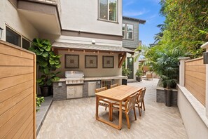 An outdoor patio with a grill, dining table, and chairs. - Beacons Beach Retreat | Steps from the Sand (Encinitas)