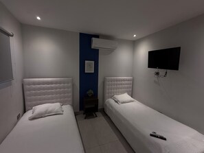 A hotel room with two beds, a wall-mounted TV, and an air conditioning unit. - Loft 33 (Monterrey)