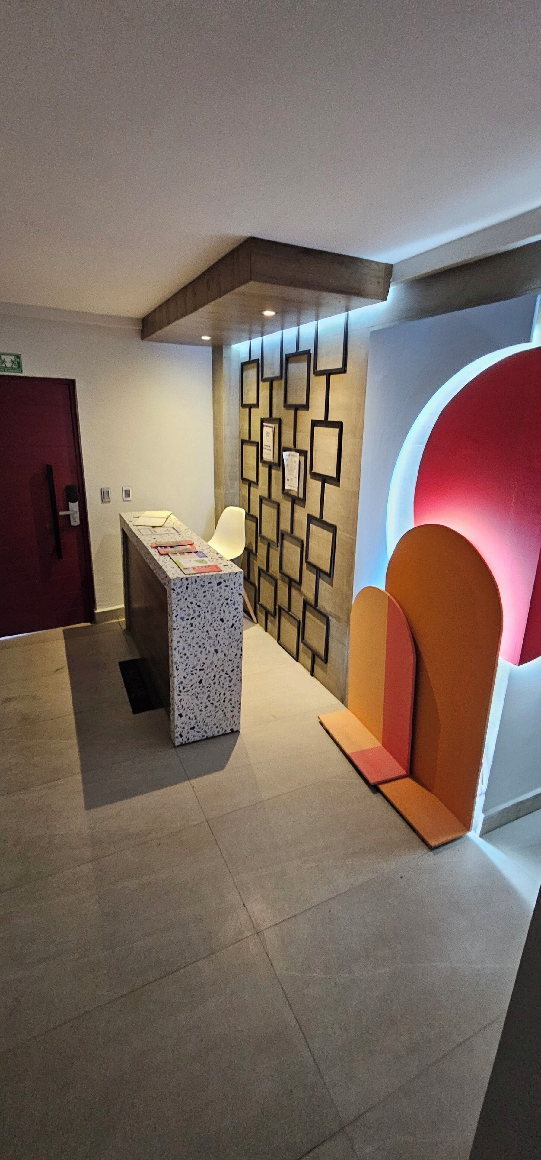 A modern lobby with a reception desk, a wall with geometric patterns, and a large red circular feature.