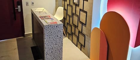 A modern lobby with a reception desk, a wall with geometric patterns, and a large red circular feature.