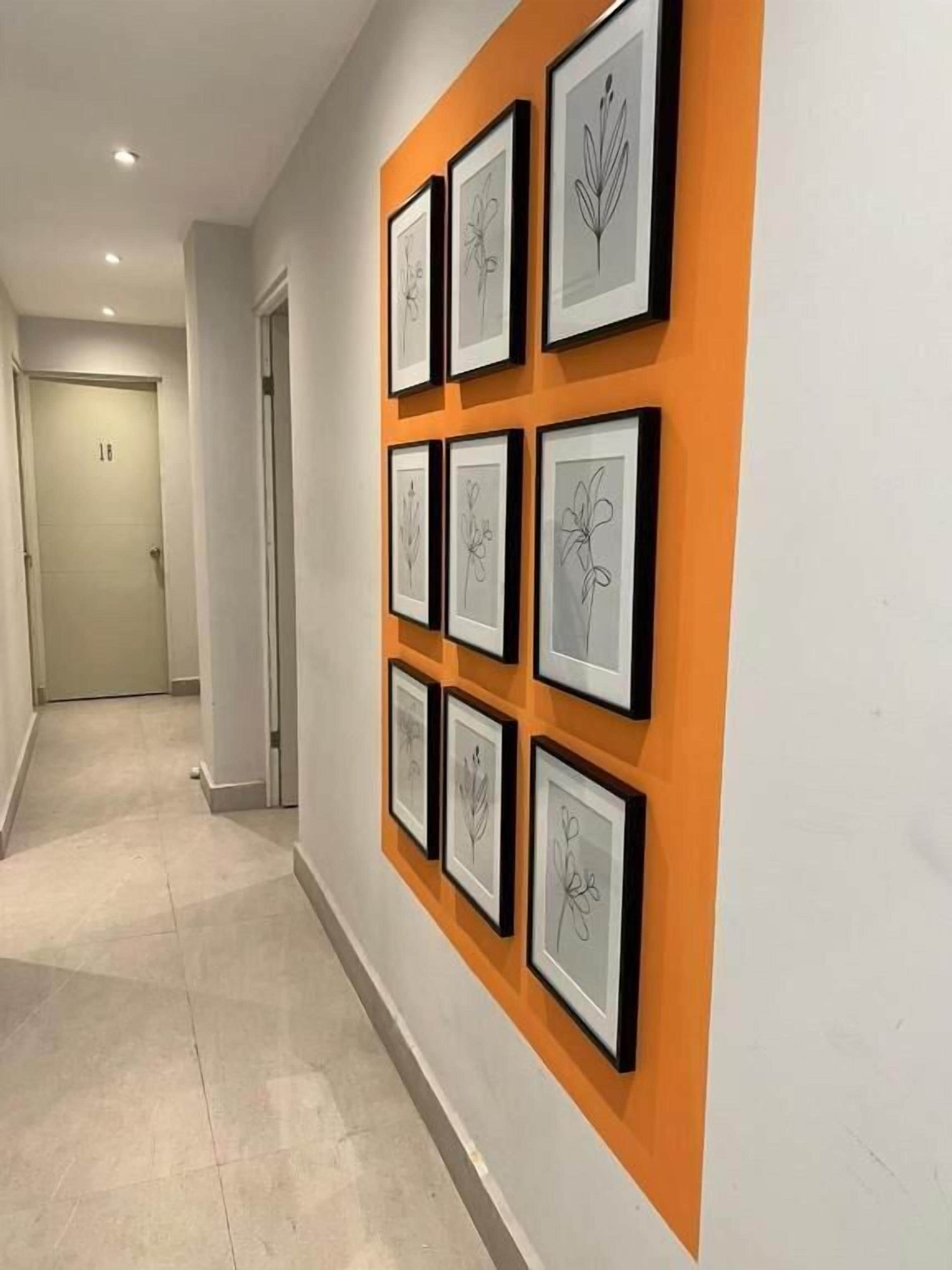 Un pasillo con obras de arte enmarcadas en la pared y una puerta con el número 18 al fondo.