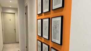 Un pasillo con obras de arte enmarcadas en la pared y una puerta con el número 18 al fondo.