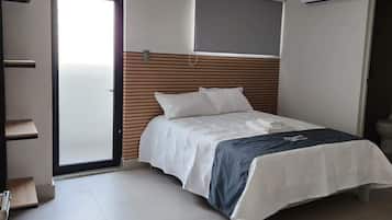 Un dormitorio con cama, cabecero de madera, ventana y un inodoro.