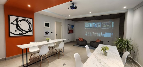A modern conference room with a long table, white chairs, and a projector screen displaying presentations. - Loft 33 (Monterrey)
