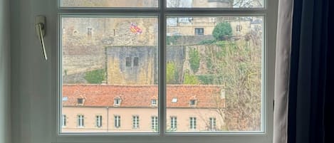 Una ventana con vistas a un edificio histórico con una torre y una bandera.