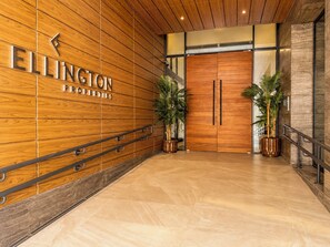 A wooden wall with the name 'ELLINGTON PROPERTIES' and a double door entrance. - Modern Chic Studio Apartment - JVC Dubai (Dubai)