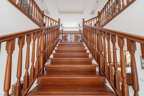 A wooden staircase with a handrail, leading to a landing with a ceiling fan. - Villa Branca Diani: Spacious 5-bedroom luxury with personalized service. (Diani Beach)