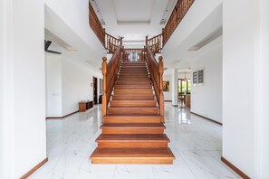 A wooden staircase with a handrail leading to a landing, surrounded by white walls and a polished marble floor. - Villa Branca Diani: Spacious 5-bedroom luxury with personalized service. (Diani Beach)