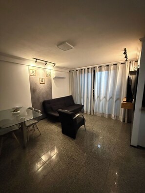 A modern living room with a glass dining table, a black sofa, and a large window with curtains. - 2-bedroom apartment in perfect Fortaleza with refreshing AC (Fortaleza)