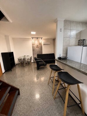 A modern kitchen with a dining area, a sofa, and a bar counter. - 2-bedroom apartment in perfect Fortaleza with refreshing AC (Fortaleza)