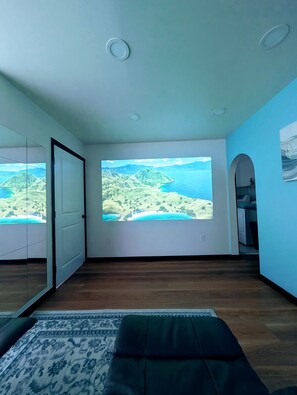 Ein Zimmer mit großem Fenster, einem Bett, einem Teppich und einer Tür.