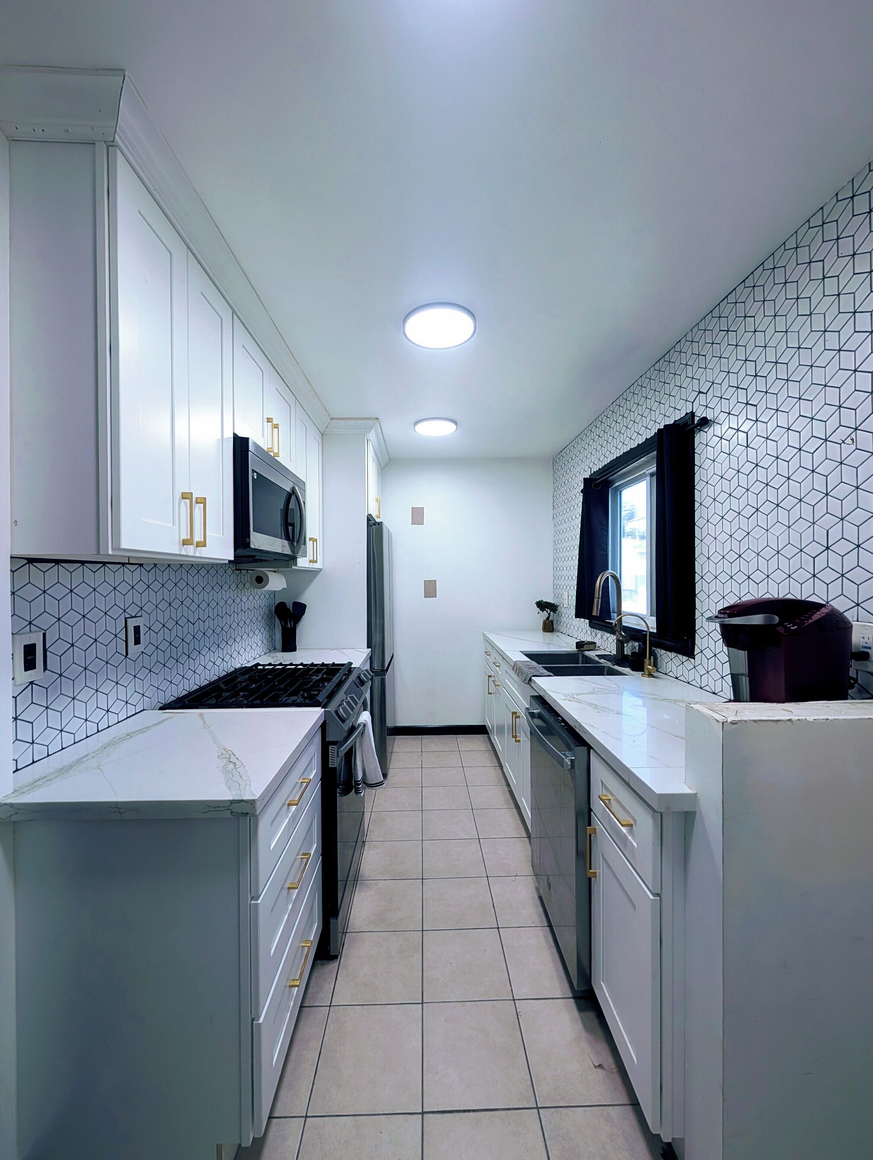 A modern kitchen with white cabinetry, a black microwave, and a tiled backsplash.